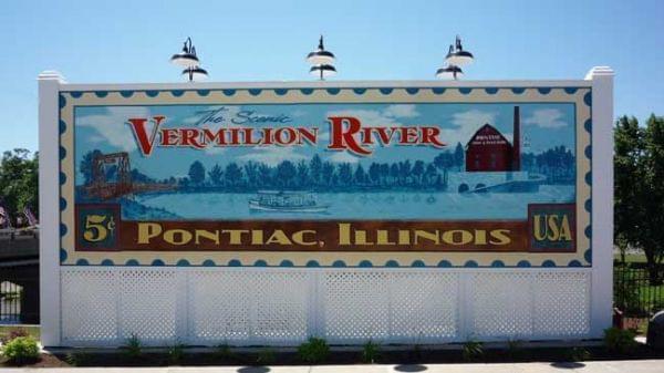 Painted sign in the shape of a postage stamp saying Vermilion River