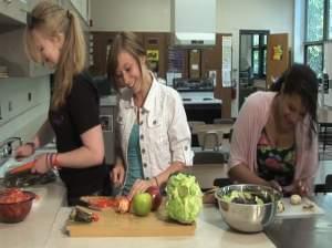 Urbana High School students Kaitlyn Breitenfeldt, Miranda Bullok, and Tessla Varvel make a salad in the school's teaching kitchen.