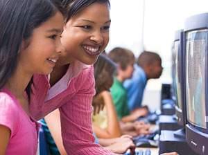 A teacher helping a student sitting in front of a computer