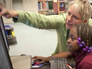 Kimberlie Kranich helping student edit video at computer.