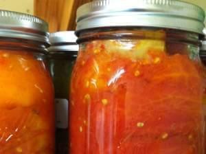 Jars of tomatoes on a shelf.