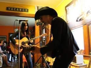 A man and a woman playing guitars in a living room.