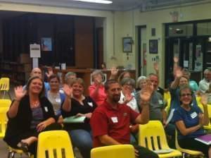 A group of people in a library waving at the camera.