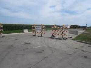 A "Road Closed" sign marks the east end of Olympian drive, where construction equipment is parked, awaiting work on the highway's extension.