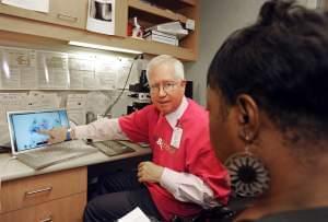 In this photo provided by College of American Pathologists, a pathologist explains a Pap test slide to Cassandra Ingram, 53, of Blaine, Minn. at North Point Health & Wellness Center's See, Test & Treat™ program Tuesday, Oct. 4, 201