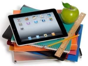 iPad tablet sitting on top of notebooks, with ruler and apple nearby