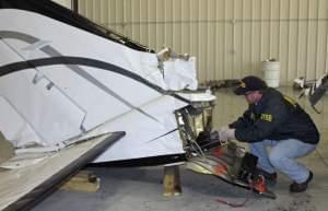 In this April 8 photo provided by the National Transportation Safety Board, air safety investigator Todd Fox examines the tail section of the Cessna 414A twin-engine aircraft that April 7.