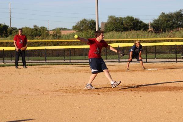 Kenny Schlax delivers a pitch while Mark Neubauer looks on.
