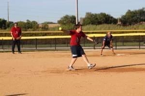 Kenny Schlax delivers a pitch while Mark Neubauer looks on.