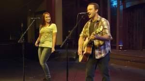 A woman sings while a man plays a guitar.