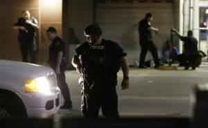 Dallas police detain a driver after several police officers were shot in downtown Dallas, Thursday, July 7, 2016. Snipers apparently shot police officers during protests and some of the officers are dead, the city's police chief said in a statem