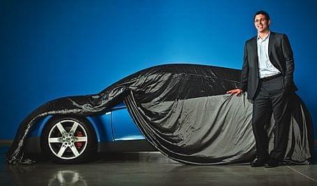 Rivian Automotive CEO R.J. Scaringe poses with a partially revealed prototype.