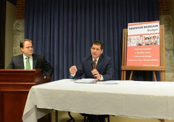 Kyle McCarter and Dan McConchie sitting at a table discussing their budget proposal.