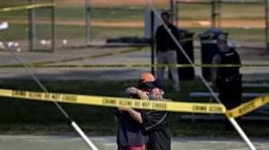 Two people embrace near the blocked-off crime scene in Alexandria, Va., where at least five people were wounded in a shooting during a congressional baseball practice Wednesday. The suspected gunman has died, officials say. 