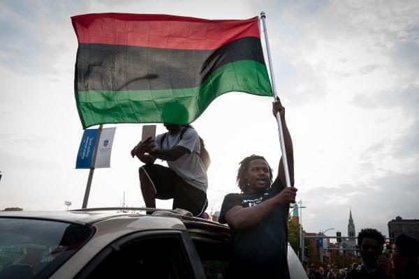 A demonstrator waves a flag from a minivan during protests Sunday over the acquittal of former St. Louis cop Jason Stockey. A third day of protests started peacefully before a smaller group smashed windows downtown.