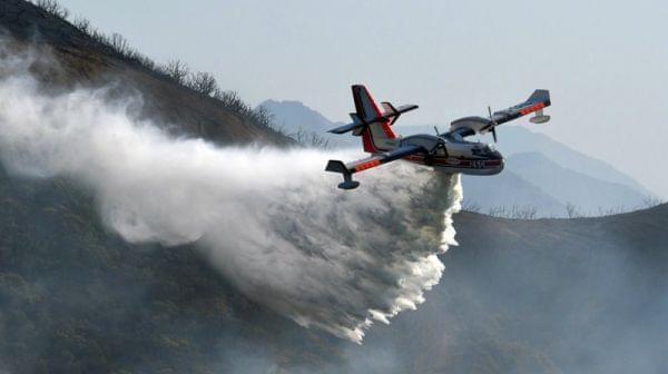 In this photo provided by the Santa Barbara County Fire Department, a Bombardier 415 Super Scooper makes a water drop on hot spots along the hillside east of Gibraltar Road in Santa Barbara, Calif., on Sunday morning. 