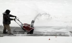 A man uses a snowblower to clear snow from a sidewalk in Chicago during a February snowstorm.