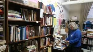 Vicki White, president of Chicago Books to Women in Prison, reads a letter sent from an incarcerated woman. She is standing in a room lined with bookcases and book shelves full of books. 