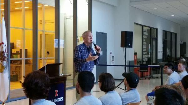 Gov. Bruce Rauner standing in front of a laboratory and speaking to a crowd. 