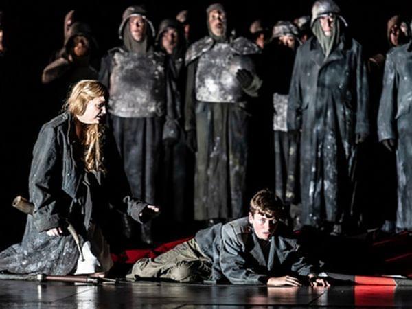 Woman stands over a boy on stage.