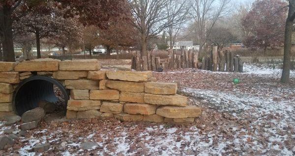 The hill-and-tunnel and the log wall at the Friendship Grove Nature Playscape in Urbana.