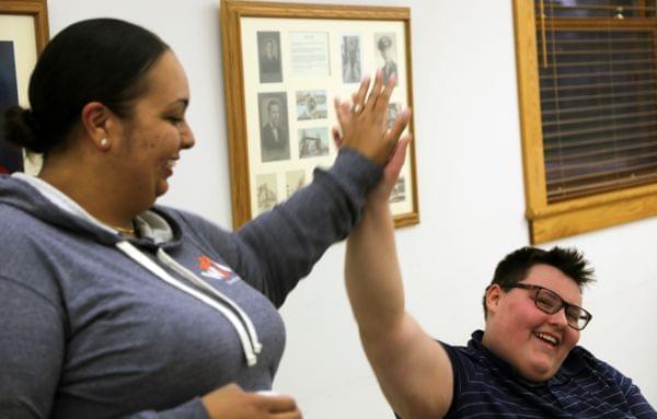 Two people smile at each other and give high-fives.