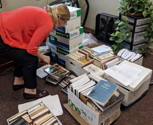 Holly Clingan crouches down to look through boxes of books removed from the EJP library at the Danville Correctional Center in an office on the University of Illinois campus. 