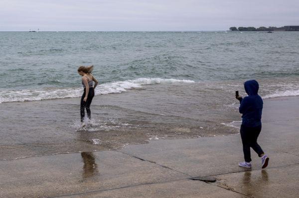 A woman jumps into the shallow water of Lake Michigan as her companion takes her picture at Chicago's Oak Street Beach, Thursday, June 20, 2019. 