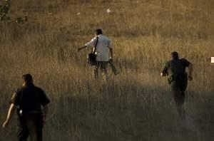 Police officers run after a photographer trying to reach a better view of a crime scene where a police officer was killed in Rosarito, Mexico, Thursday, Oct. 23, 2008.