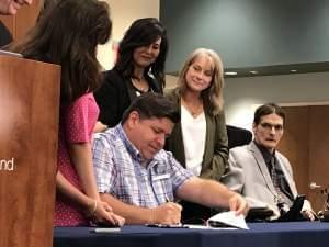 Gov. J.B. Pritzker, flanked by supporters and legislators, signs a law expanding school children's ability to use medical marijuana at school. The governor approved expansions to the Medical Marijuana program on Aug. 9. 