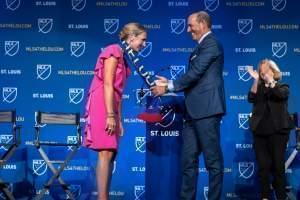 Major League Soccer Commissioner Don Garber drapes an MLS scarf that reads "St. Louis" over Carolyn Kindle Betz, who leads the ownership group for St. Louis' new professional soccer team. 