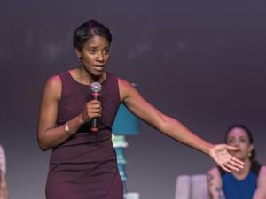 Women standing on stage talking with arm extended