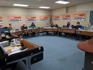 Urbana School board members seated around a long U shaped table during their board meeting