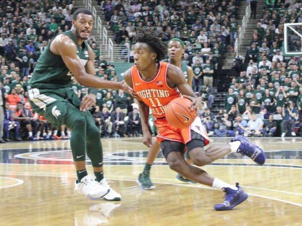Illini guard Ayo Dosunmu drives spast Spartan defenders.