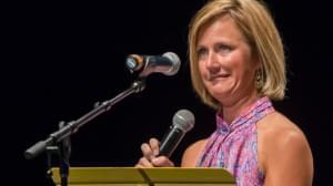 Woman stands on stage with microphone