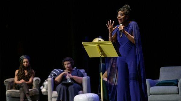 woman stands on stage with a microphone behind a stand