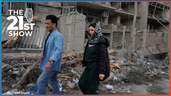People walk past buildings damaged during a strike on a police station during ongoing, joint U.S.-Israeli military attacks in Tehran, Iran, Monday, March 2, 2026.