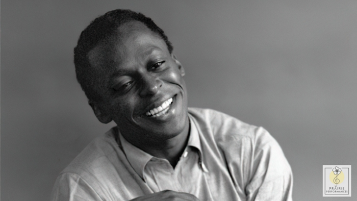 Miles Davis smiles, looking relaxed with his head tilted to the side.
