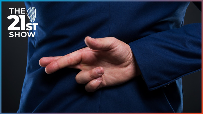 a man wearing a dark blue suit has his fingers crossed behind his back