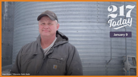 A man stands in front of a grain bin.