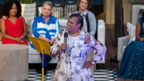 woman stands with microphone on stage