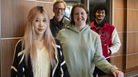 Four people stand at a railing inside Campbell Hall on the University of Illinois Urbana-Champaign campus.