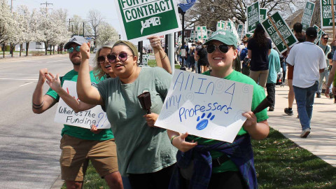 Eastern Illinois University mental health master's students Natalie Roberson (second from right) and Amina Feder (right) urge drivers to honk in support of the faculty and staff strike on Monday, April 10.