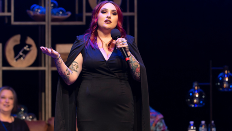 Woman in black dress holding microphone on stage