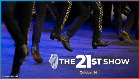 a close-up view of men dancing: perhaps six pairs of legs wearing identical black boots and black pants embroidered with gold stitching and buttons down the front