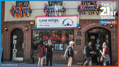 people who appear to be tourists mill in front of a red-brick building with 
