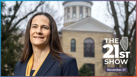 a white woman with broan hair wearing a navy blazer with a maize-colored scarf stands in front of a older building with a dome on top