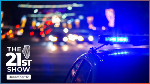 blue lights atop a police car are in the foreground with blurred lights of other cars and street lamps in the background