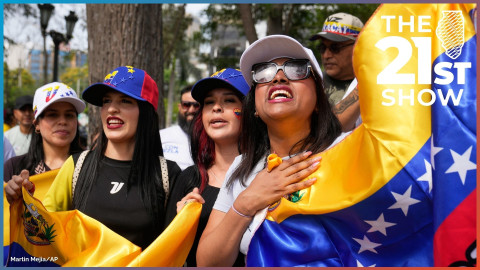 Four women smile while wearing baseball caps and holding flags representing Venezuela.