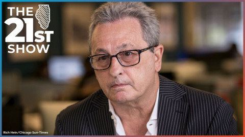 a white man in glasses is wearing a white button-down shirt, open at the collar, and a pinstripe suitcoat